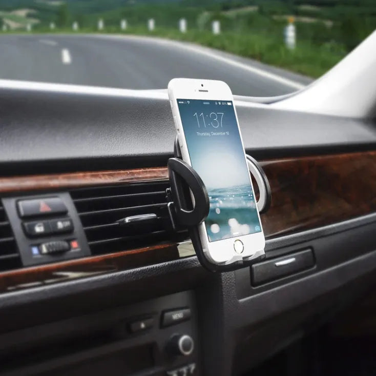 Black plastic car air vent phone holder mounted on car dashboard with mobile phone securely in cradle