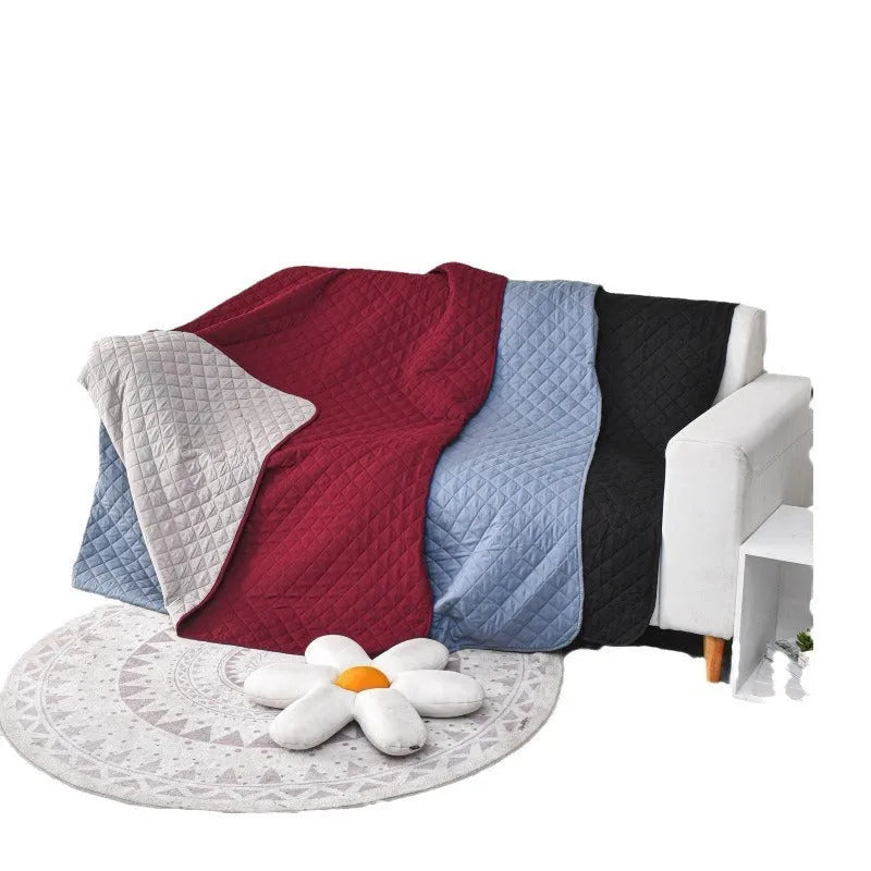 Reversible dog blanket showing two colours, laid flat on a sofa as a protective cover