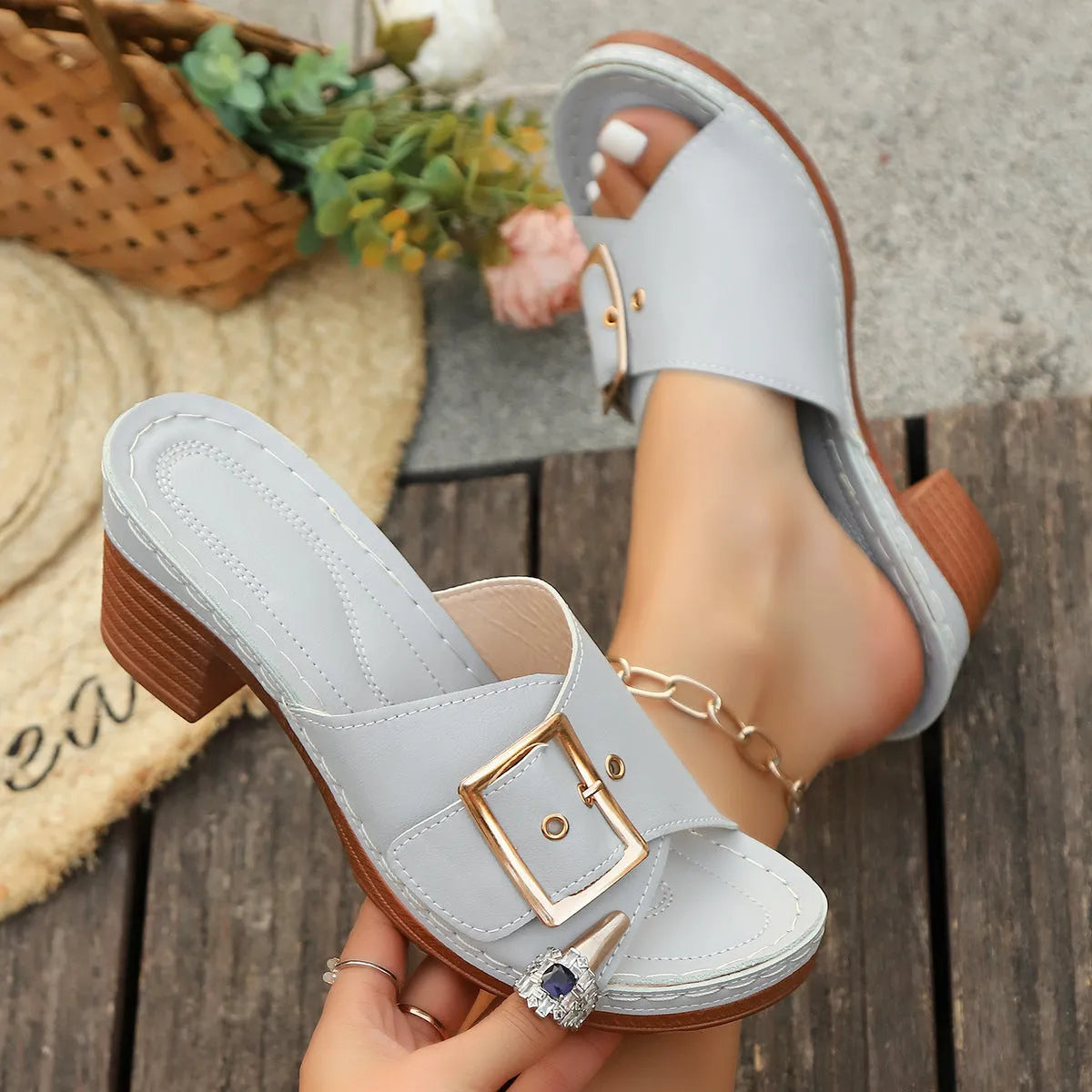 Women's black chunky heel slippers with a large silver metal buckle strap on a rubber sole.