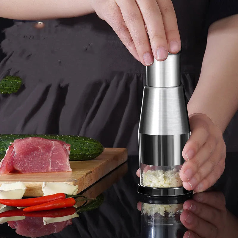 Black manual garlic crusher onion chopper with stainless steel blades on a kitchen counter