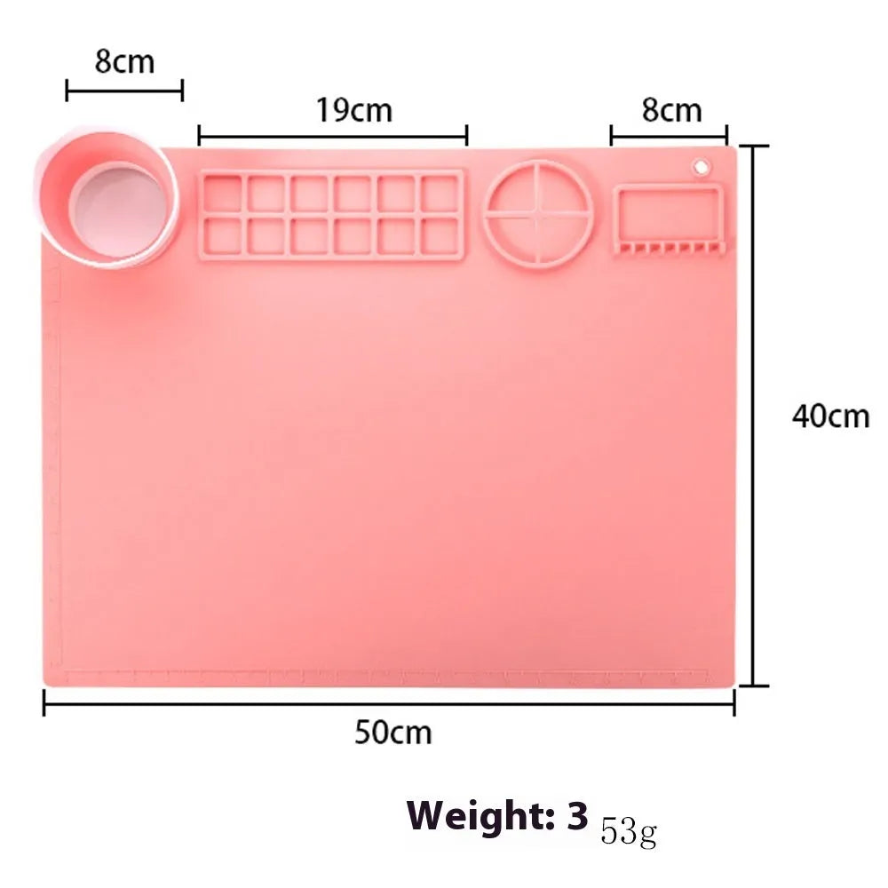 Light blue silicone painting mat with an integrated bowl on one side, positioned on a wooden table.