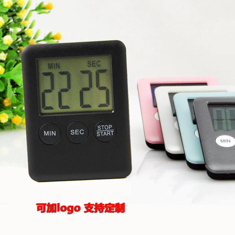 Black and white digital kitchen timer with LCD screen and magnetic back on a fridge