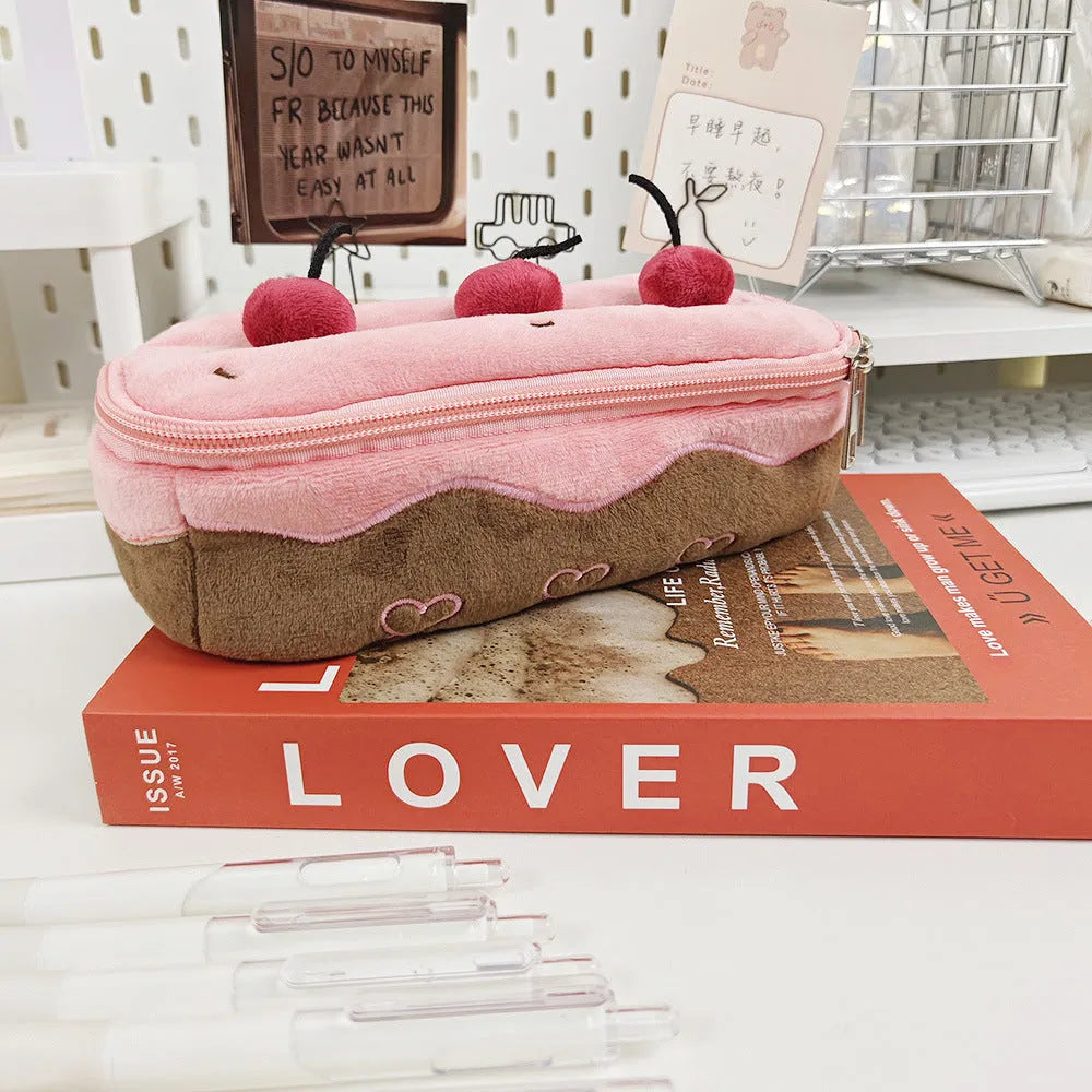 Red velvet pencil bag with cherry cake pattern print, open to show empty interior.