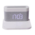White wireless charging desktop clock with LED display and foldable stand on a wooden desk.