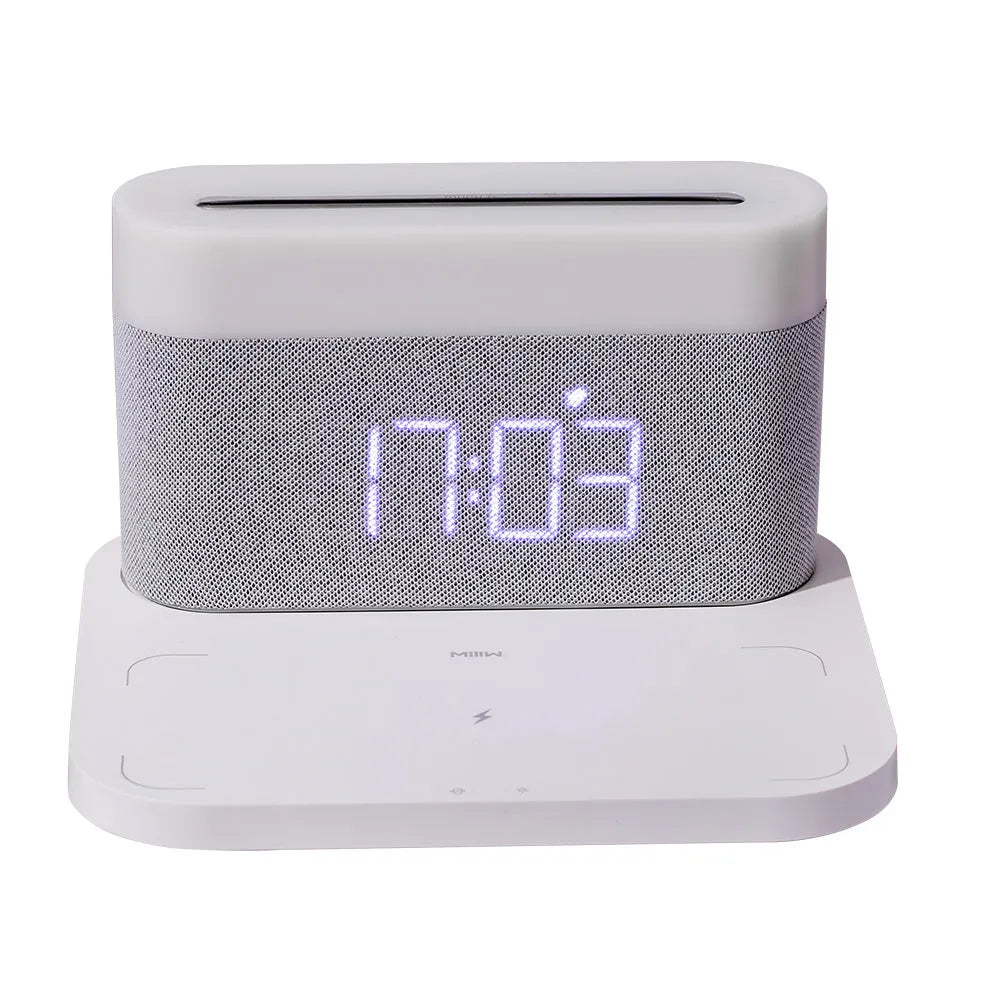 White wireless charging desktop clock with LED display and foldable stand on a wooden desk.