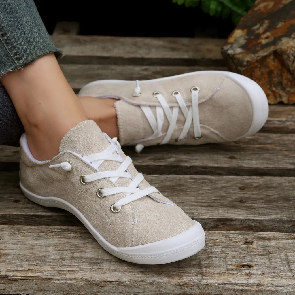 Women's creamy white low-top fabric sneakers with a casual design and rubber sole.