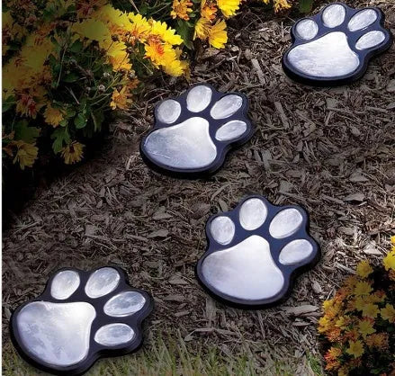 Set of four black bear paw print solar LED garden lights with a central solar panel pole on grass.