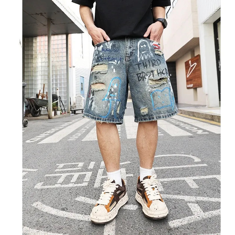 Blue ripped men's denim shorts with graffiti pattern and straight-leg cut.