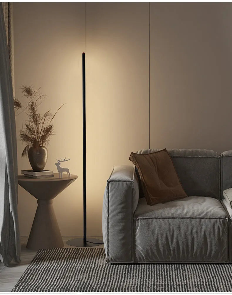 Simple modern vertical aluminium alloy floor lamp in silver, shown beside a sofa.