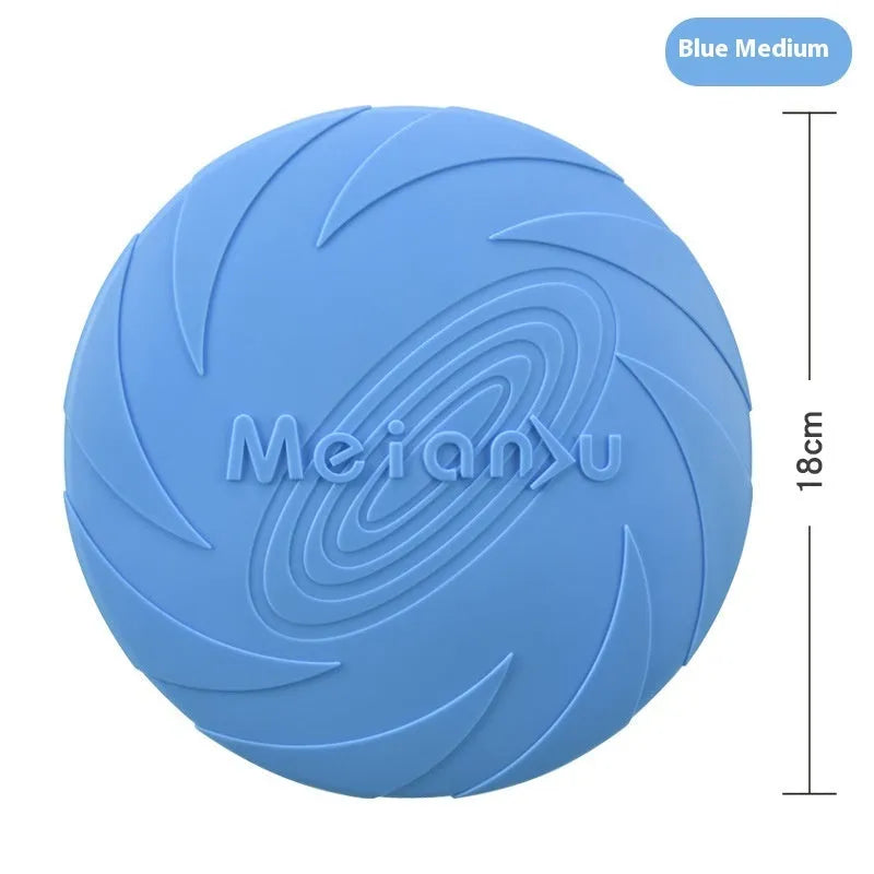 Soft rubber dog frisbee toy in blue, shown on grass for scale.