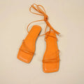 Women's flat sandals with ankle ring bandage cloth detail in white, black and orange.