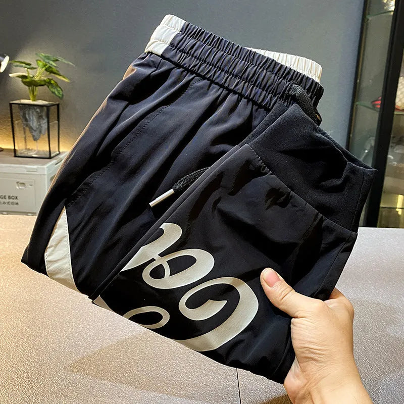Man wearing black cropped cotton trousers with an ankle banded cuff.