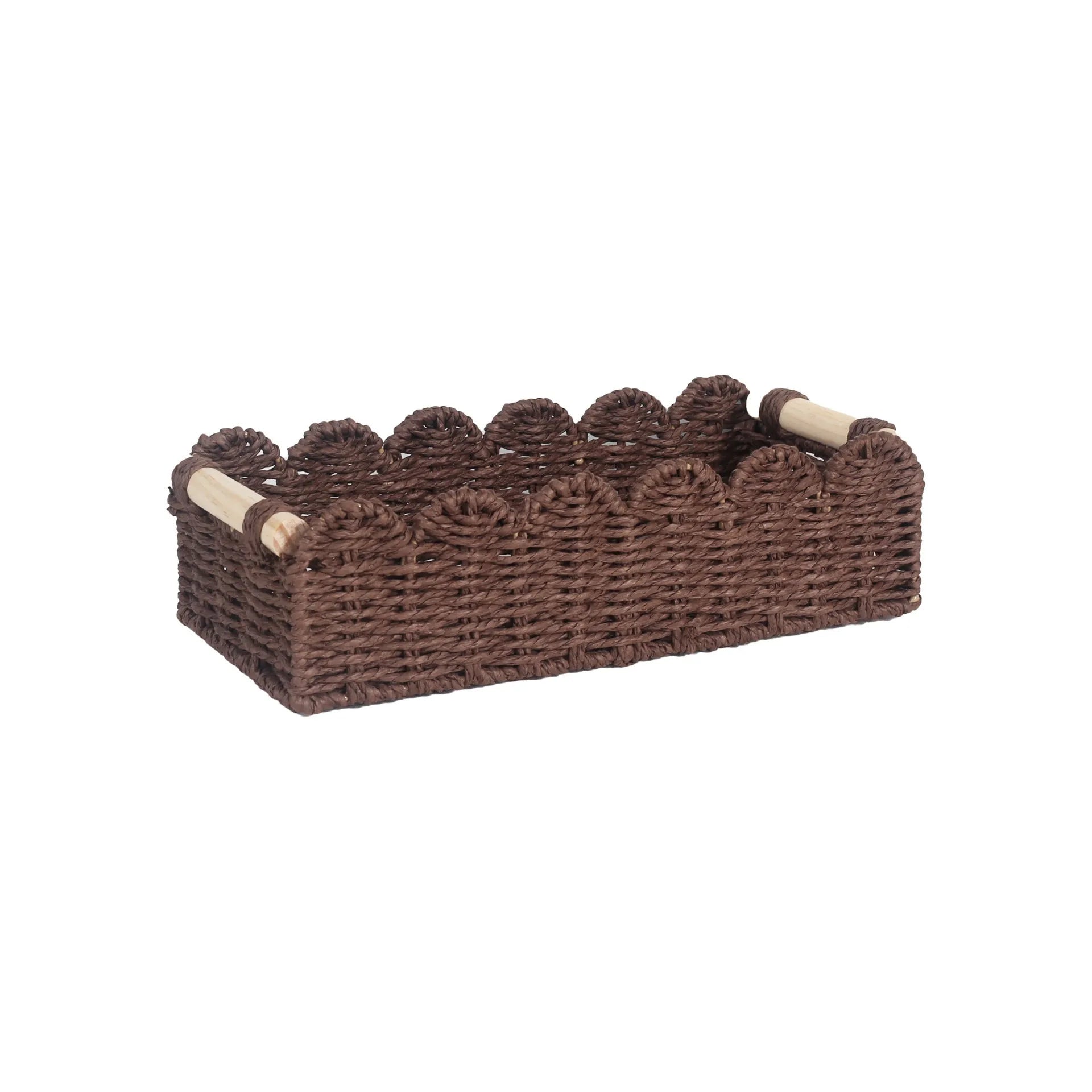 Modern woven paper storage basket in khaki colour on a wooden desktop, holding remote controls and pens.