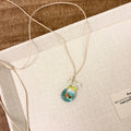 Women's necklace with a coloured glaze skirted joker pendant on a cotton and linen clavicle chain.