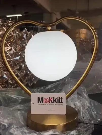 White plastic heart shaped night light with glowing centre on a wooden table