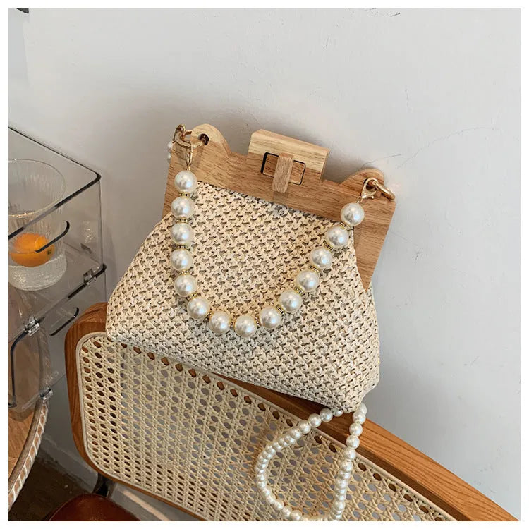 Women's woven straw shoulder bag with pearl chain strap showing interior organiser compartments