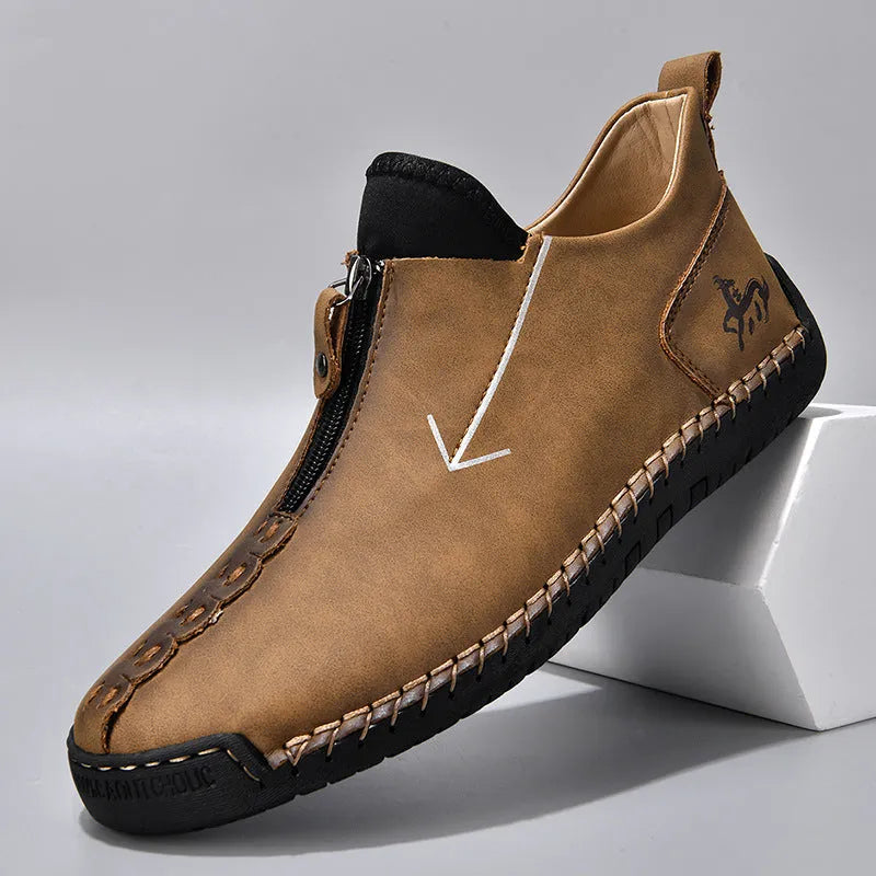 Men's black leather boots with a front zipper and round toe, showing hand-stitched sole detail.