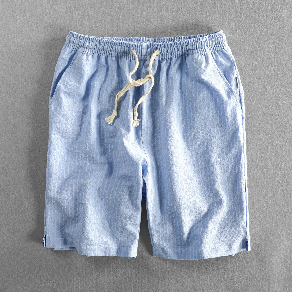 Man wearing striped light blue cotton casual shorts with a mid waist and loose straight fit.