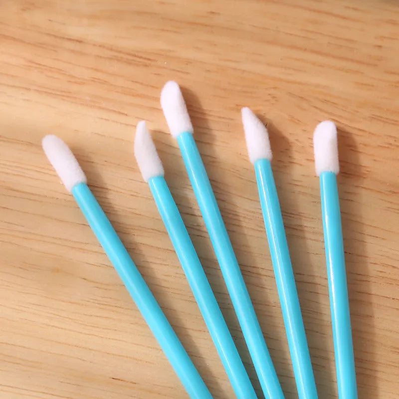 Pack of disposable lip brush applicators with flocked heads and black handles on a white background.