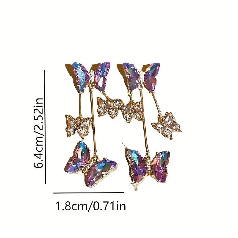 Silver toned earrings with a blue purple butterfly, crystal flowers, and a long tassel drop chain.