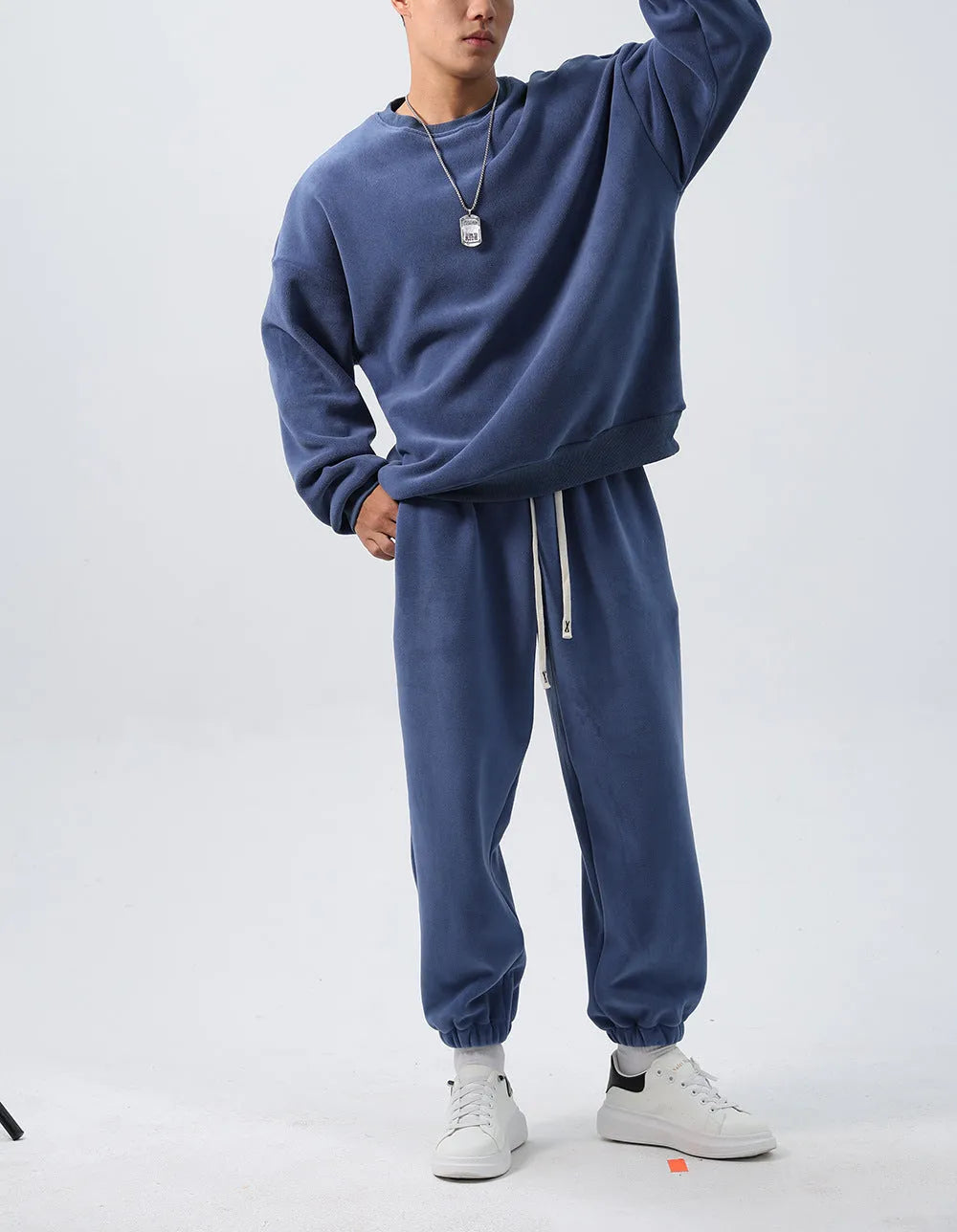 Men's black polar fleece sports suit with loose crew neck jacket and padded trousers on a hanger.