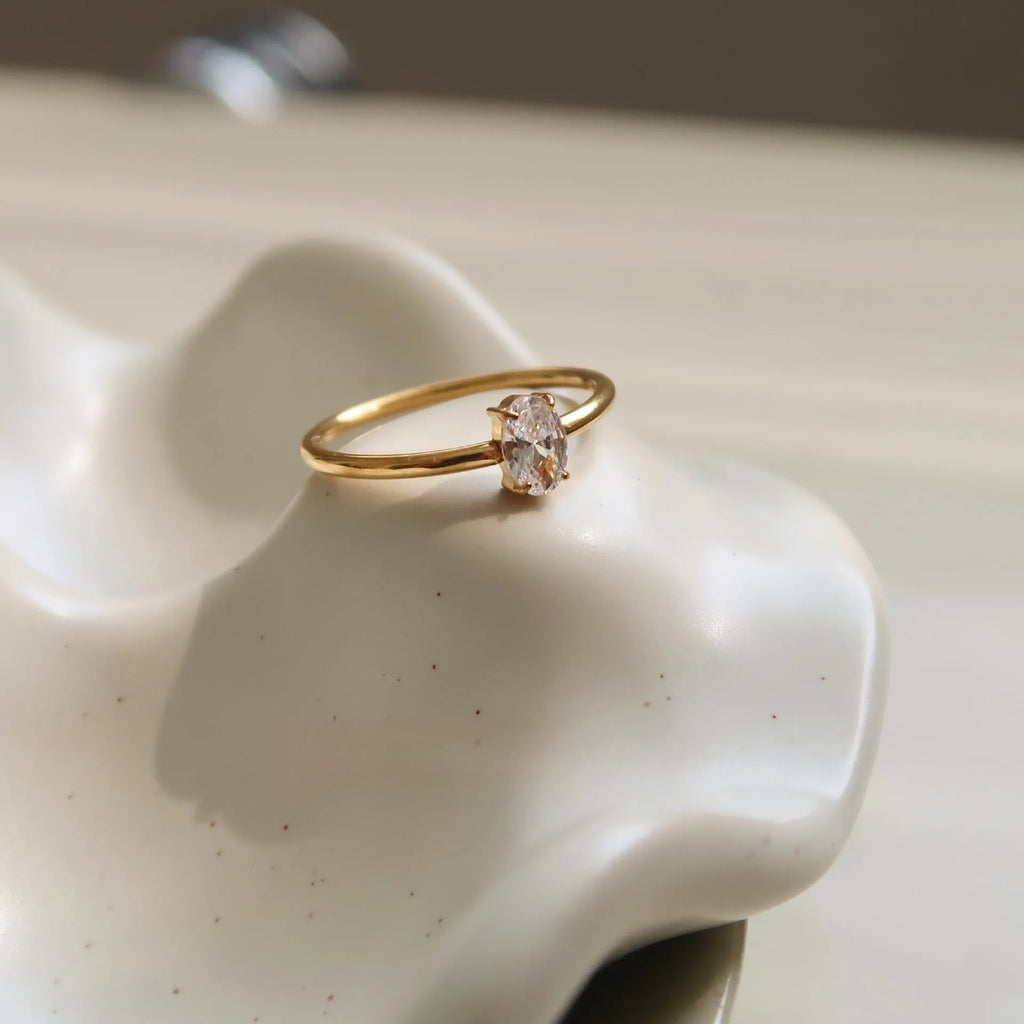 Golden electroplated stainless steel ring showing heart and oval shape designs on a hand.