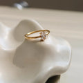 Golden electroplated stainless steel ring showing heart and oval shape designs on a hand.