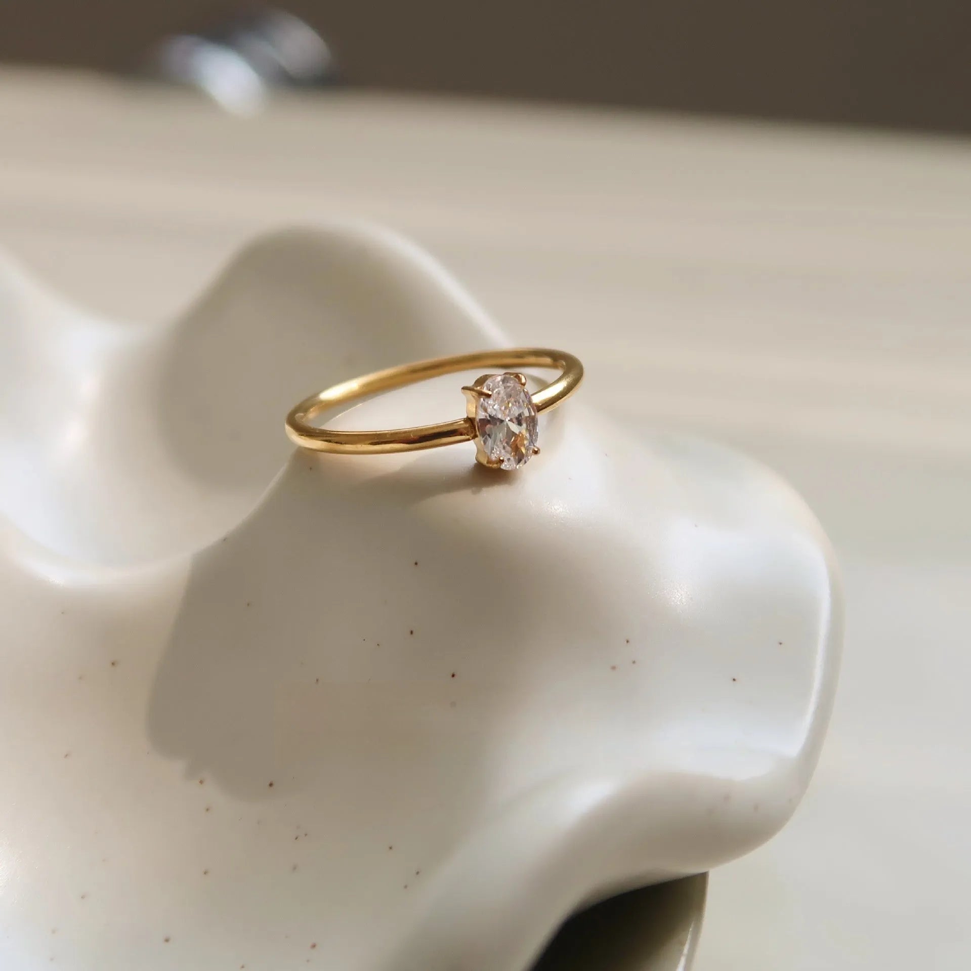Golden electroplated stainless steel ring showing heart and oval shape designs on a hand.