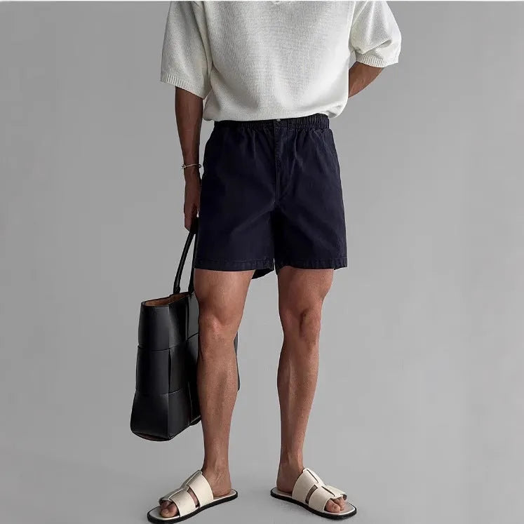 A pair of loose-fitting cotton sports shorts in khaki colour on a white background.
