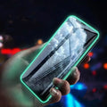 Luminous full cover tempered glass screen protector glowing on an iPhone in a dark setting.