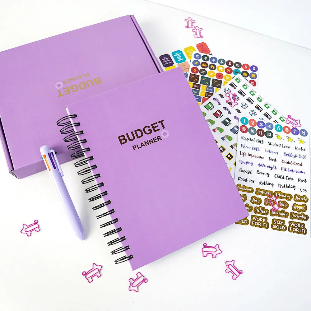 Purple coil-bound budget notebook with daolin paper pages, pen, stickers, and paper clips for financial planning