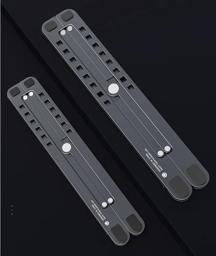 A folded silver aluminium laptop stand next to an open laptop, showing its thin profile and adjustable angle mechanism.