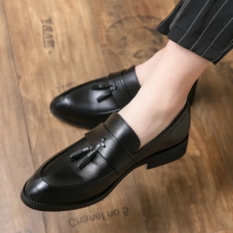 Men's black slip-on loafer with tassel detail and rubber sole on white background