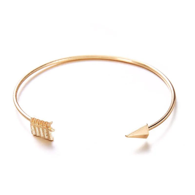 Gold-coloured women's vintage cuff bracelet with an arrow knot detail on an alloy band.