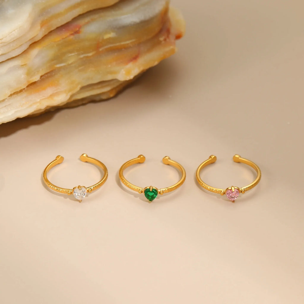 Open ended stainless steel ring with a geometric heart shape and inlaid zircon stone in white, pink, or green.