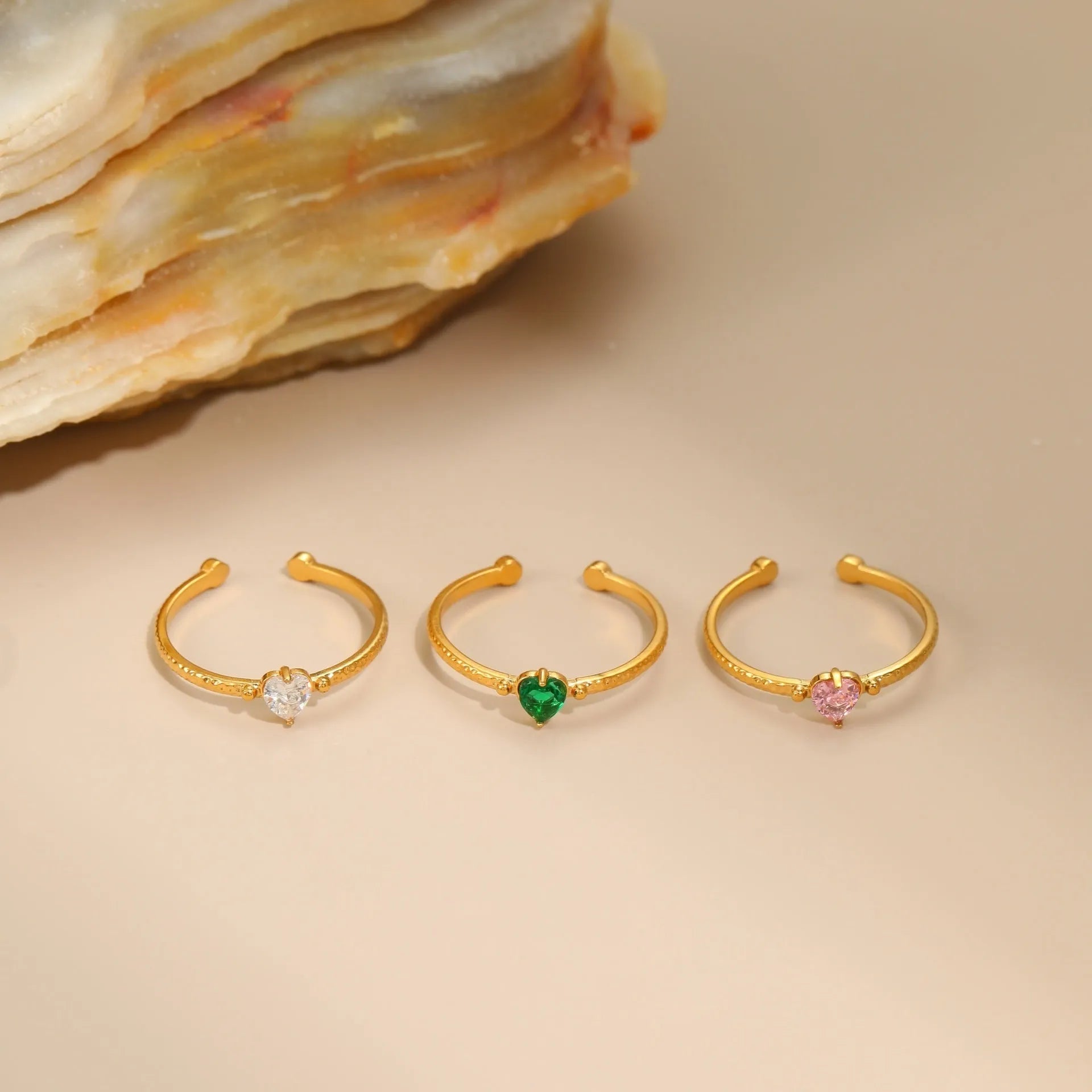Open ended stainless steel ring with a geometric heart shape and inlaid zircon stone in white, pink, or green.