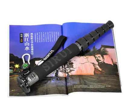 Black carbon fibre telescopic camera monopod extended to full height on a grey background.