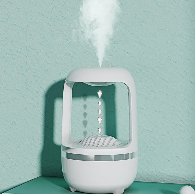 White anti-gravity water droplet humidifier on a table with USB cable, showing mist output