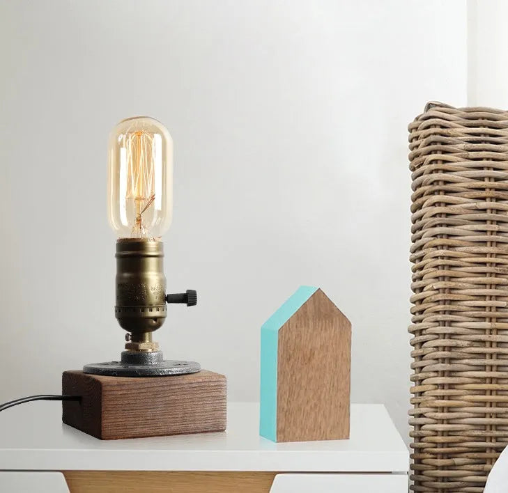 Industrial-style wooden and iron water pipe table lamp on a surface, showing its compact size.