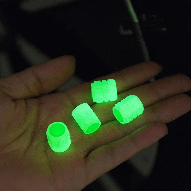 Set of four luminous rubber car valve caps glowing on a dark background.