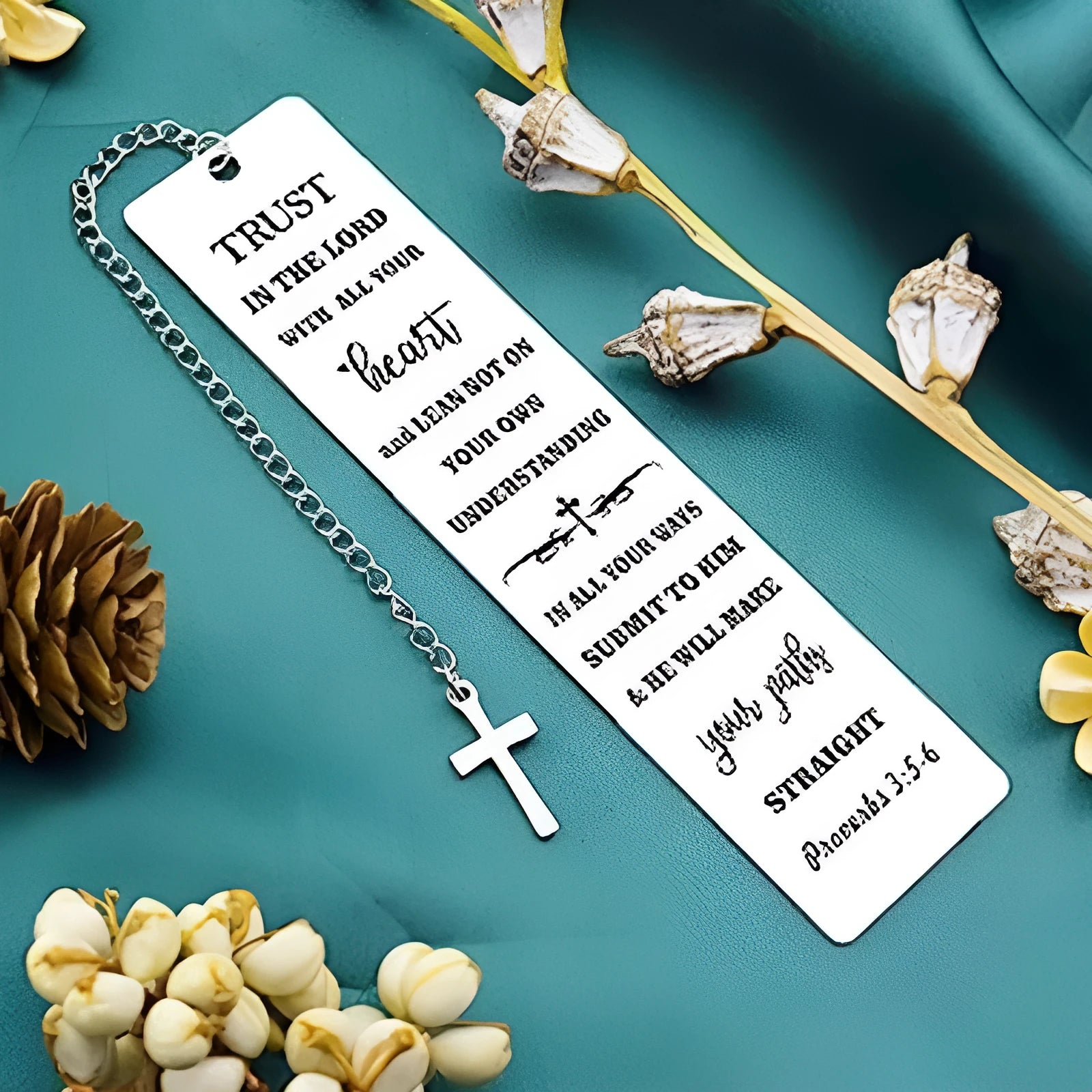 A polished stainless steel bookmark with an engraved inspirational verse, shown against an open book.