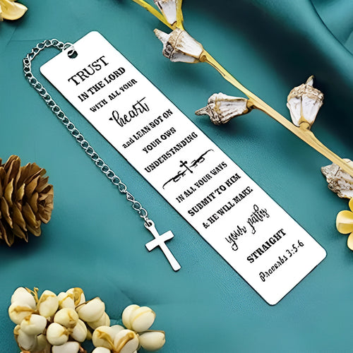 A polished stainless steel bookmark with an engraved inspirational verse, shown against an open book.