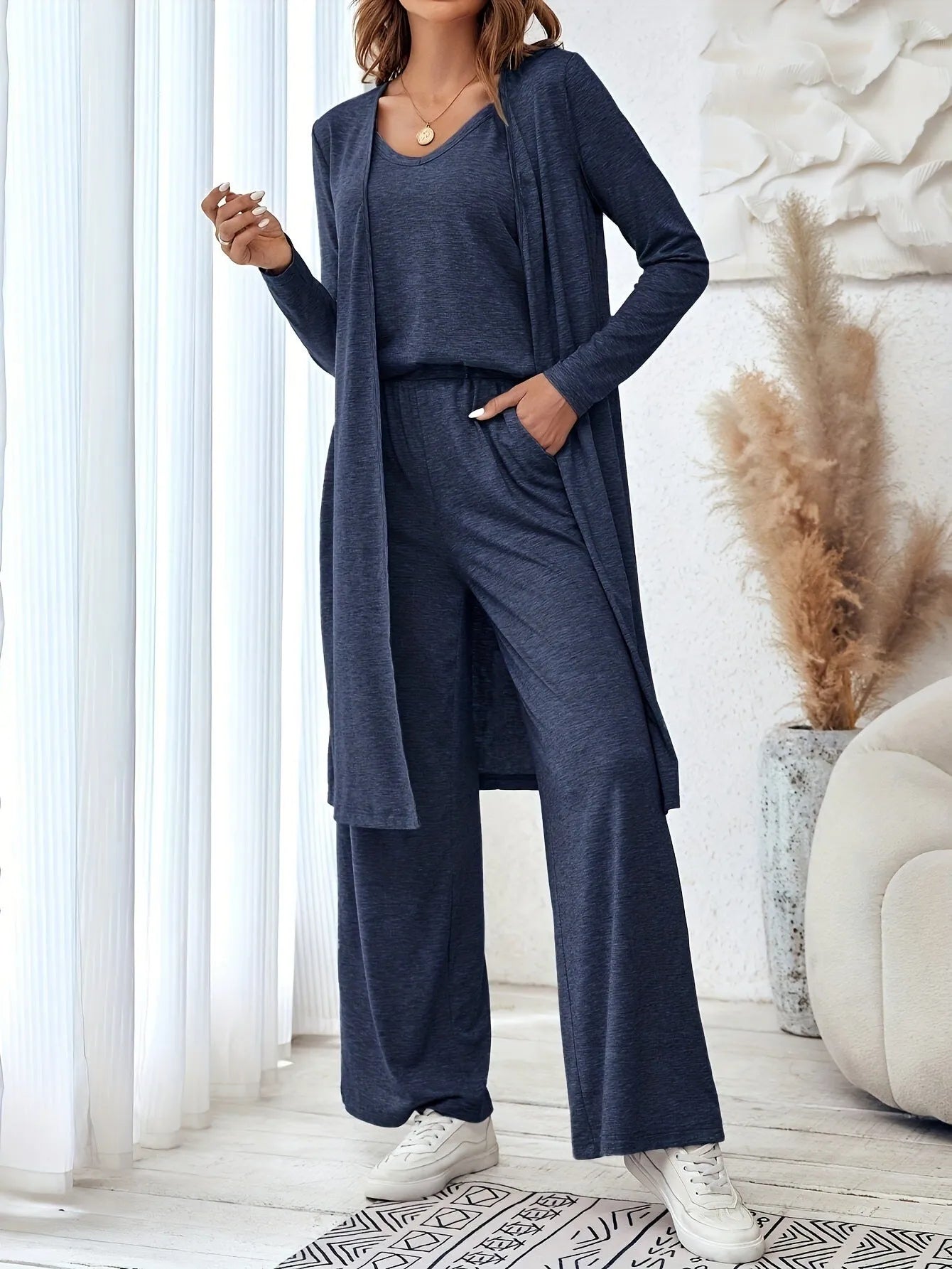 Blue women's polyester suit set with sling top, long cardigan, and trousers on a hanger.