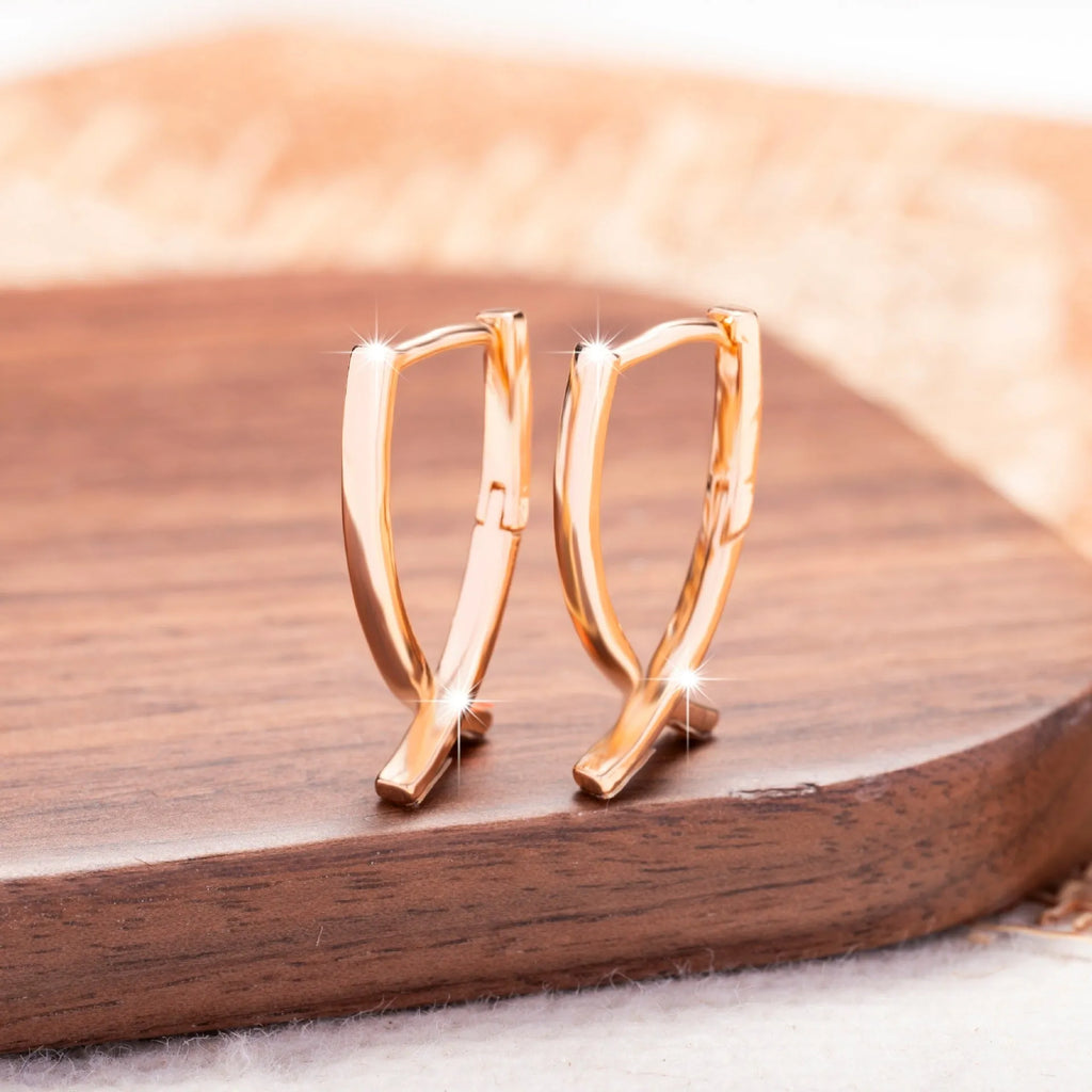 A pair of rose gold cross shaped fashion earrings on a copper alloy base.
