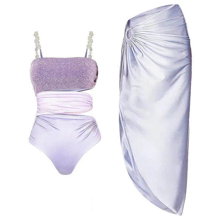 Purple one-piece swimsuit and matching wrap skirt set laid flat.