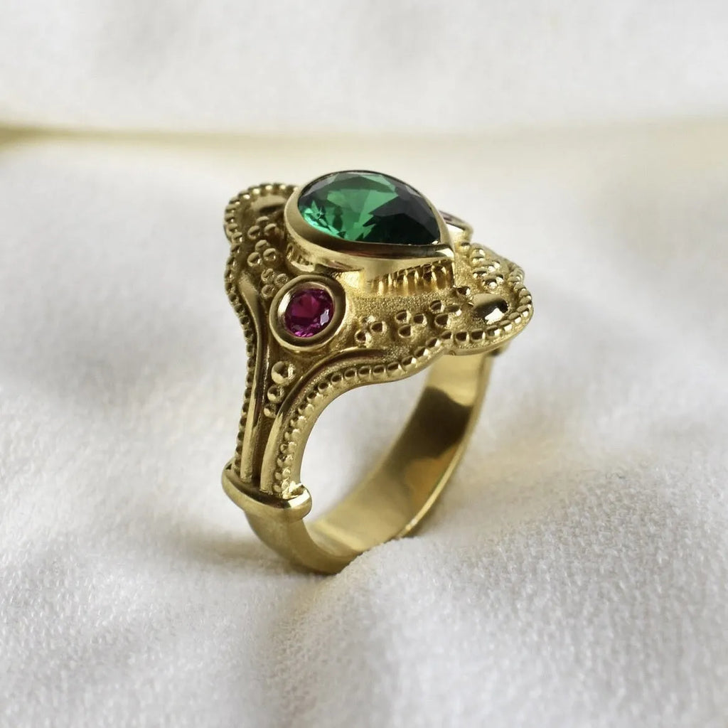 A gold-coloured women's ring with a geometric shape on a plain background.