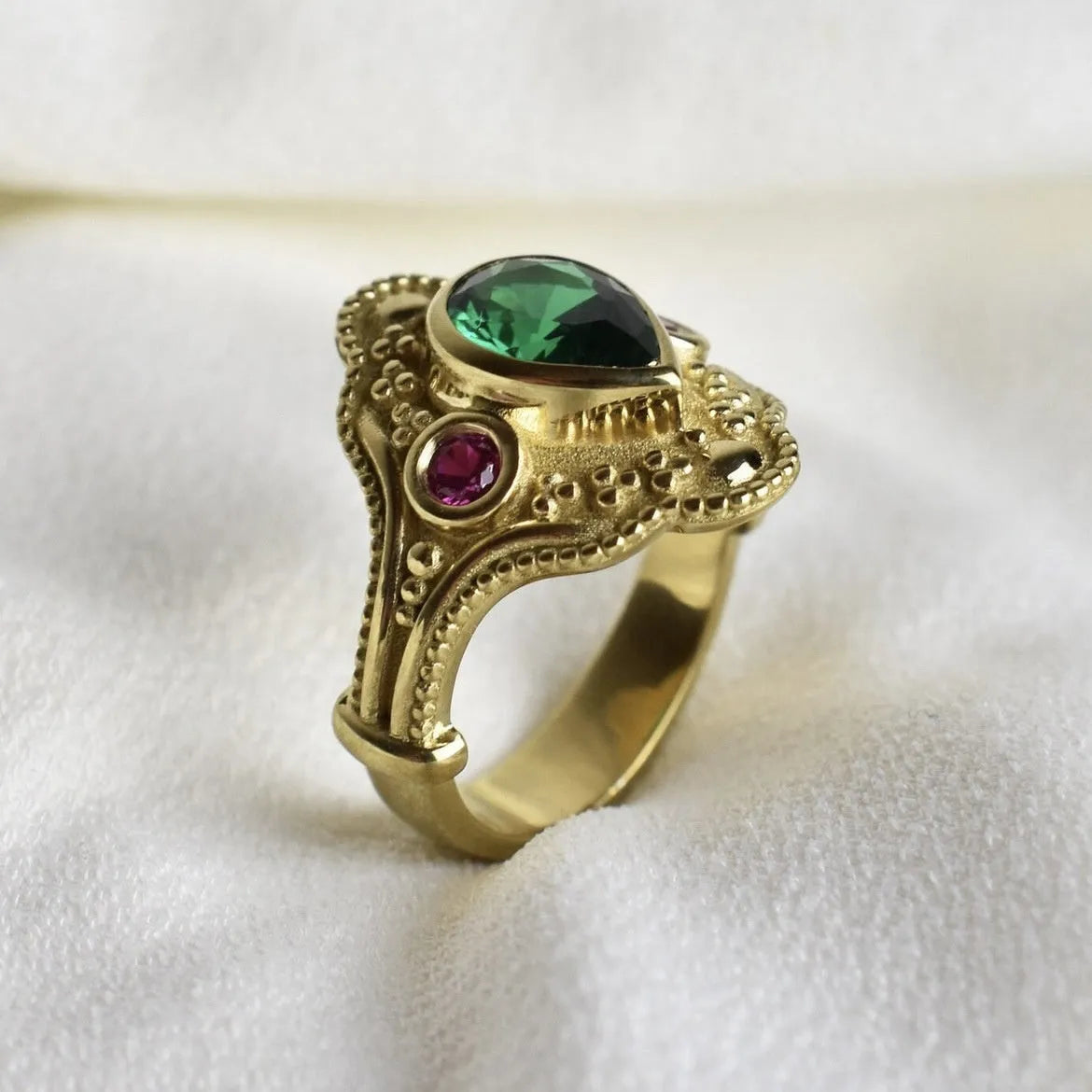 A gold-coloured women's ring with a geometric shape on a plain background.