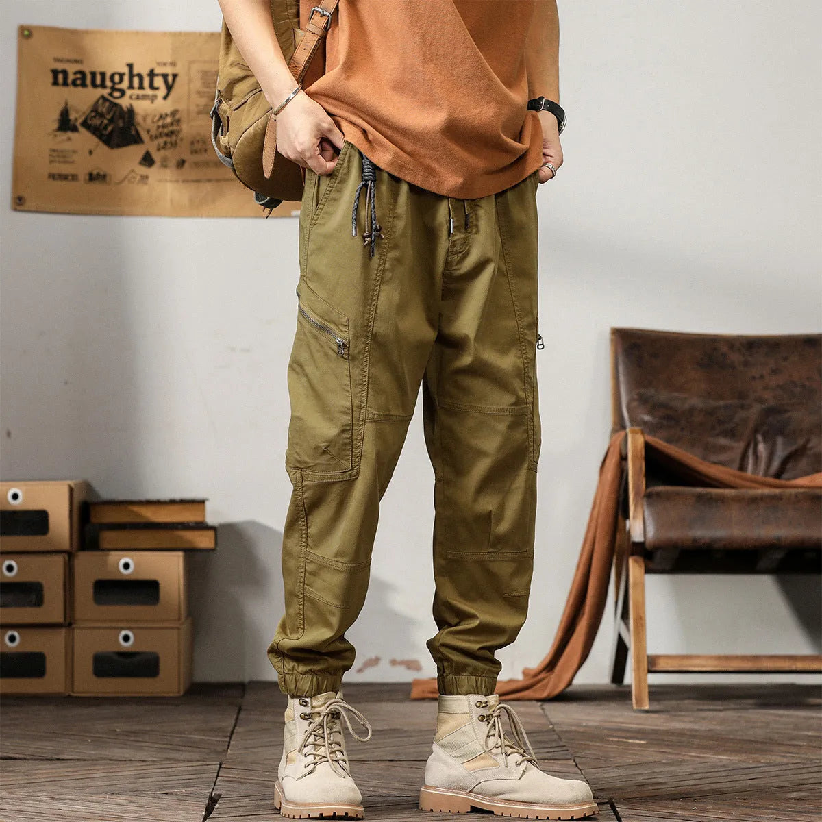 Men's khaki cotton tapered harem pants with ankle bands and a zip fly, laid flat.