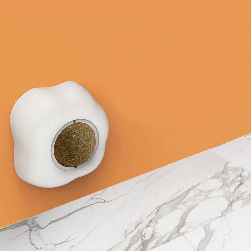 Soft plush catnip ball toy in fried egg shape stuck to a wall, with a cat playing.