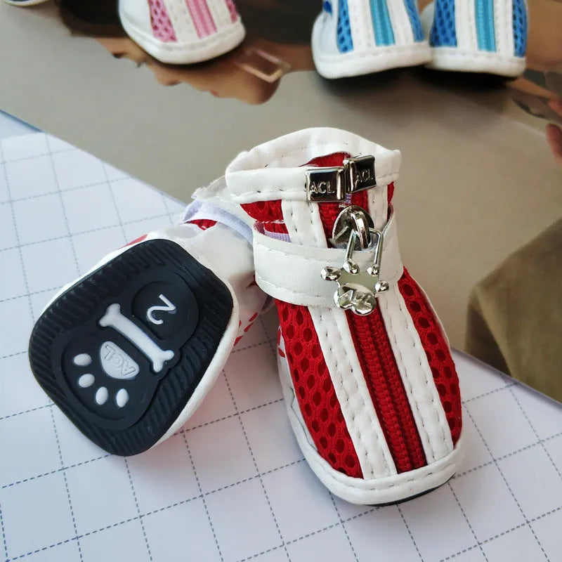 Four blue cloth dog shoes with zipper closures, showing non-slip soles, laid out on a white surface.